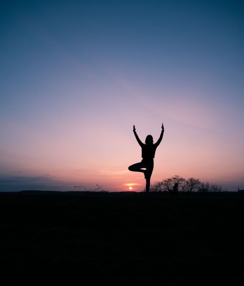 Silhouette d'une personne en équilibre sur une jambe au coucher du soleil, illustrant le test d'équilibre lié à la longévité